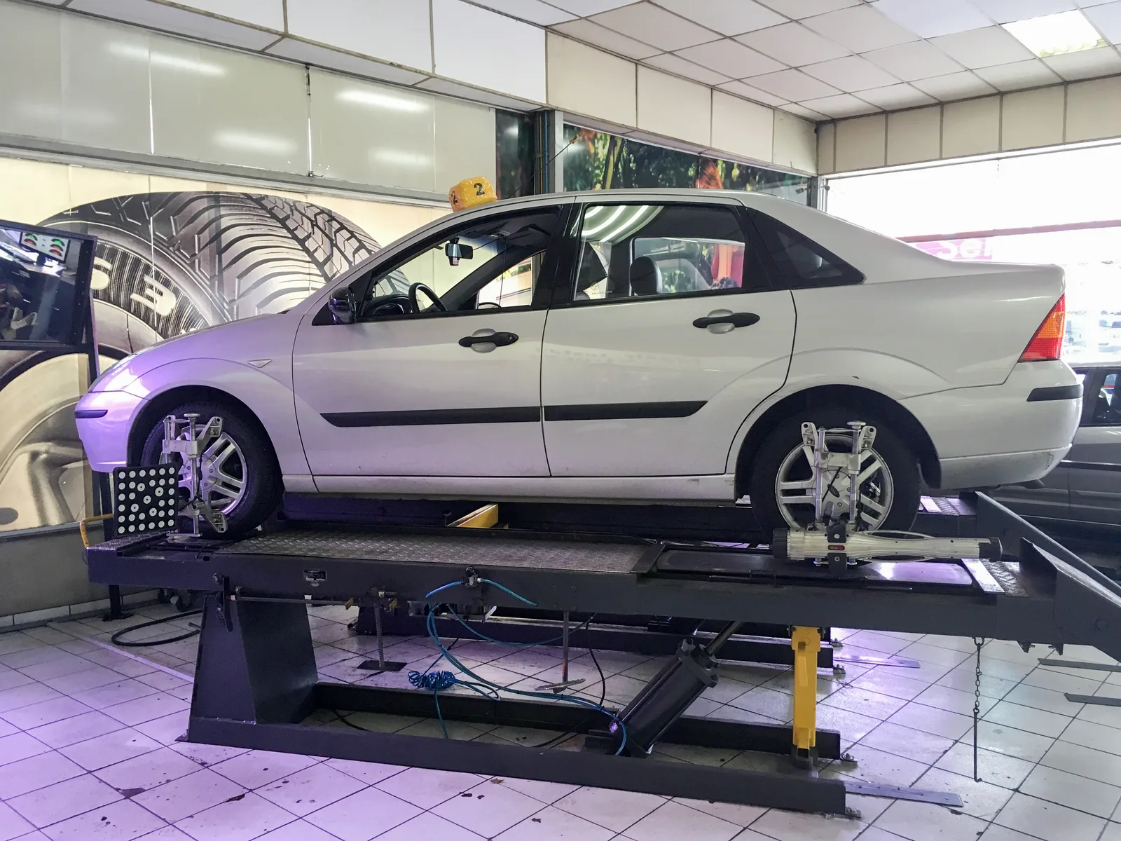 Contrôle de l'alignement des roues d'un véhicule sur un pont élévateur en atelier.