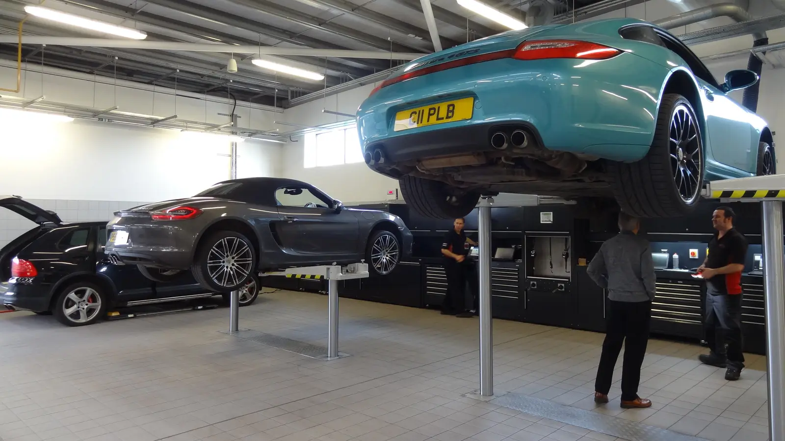 Deux Porsche 911 sur des ponts élévateurs dans un atelier mécanique.