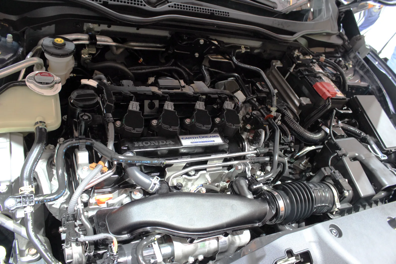 Compartiment moteur ouvert d'une Honda Civic X, cache-moteur floqué du logo Honda et de la mention Earth Dreams Technology.