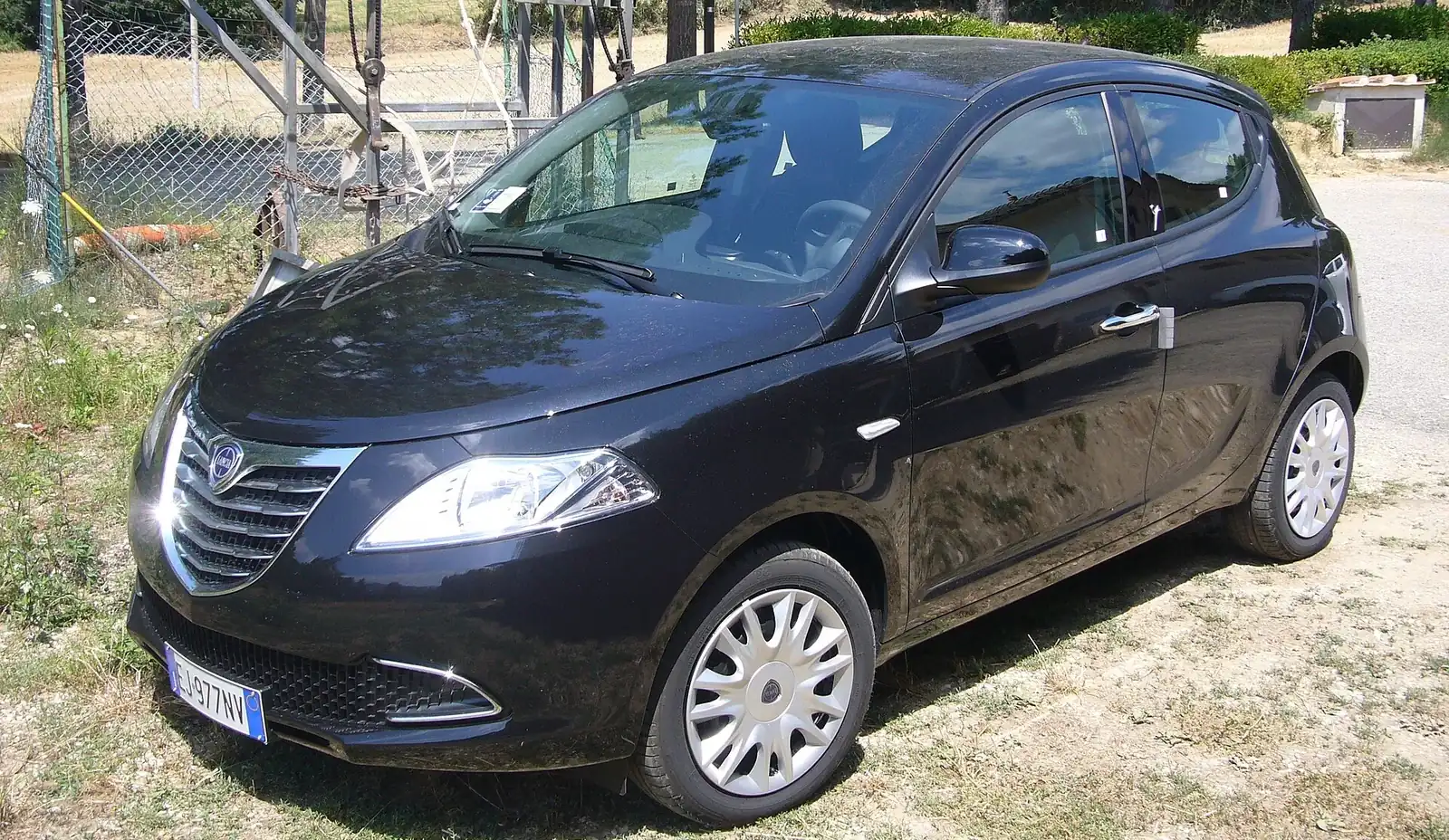 Lancia Ypsilon noire de 2011 de trois-quarts avant, garée sur un chemin de terre en Toscane.