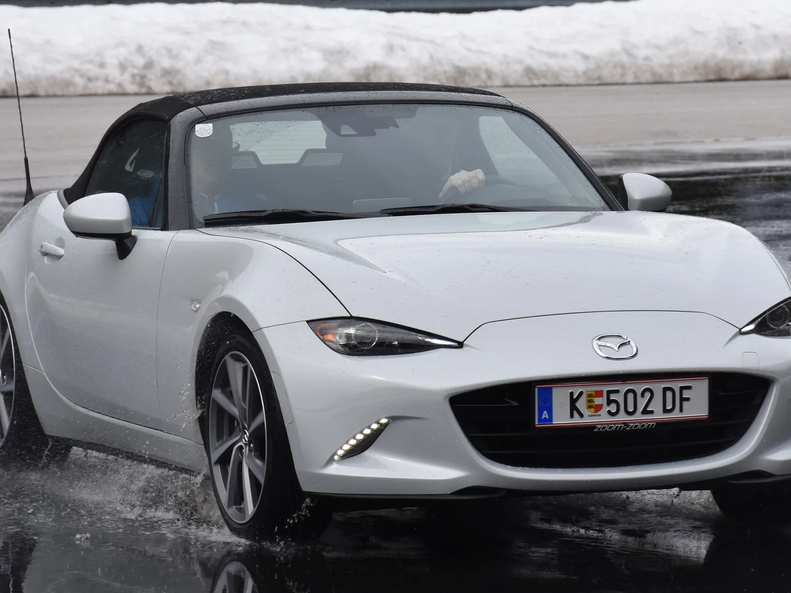 Mazda MX-5 (ND) blanche de trois-quarts avant, roulant sur une piste mouillée.