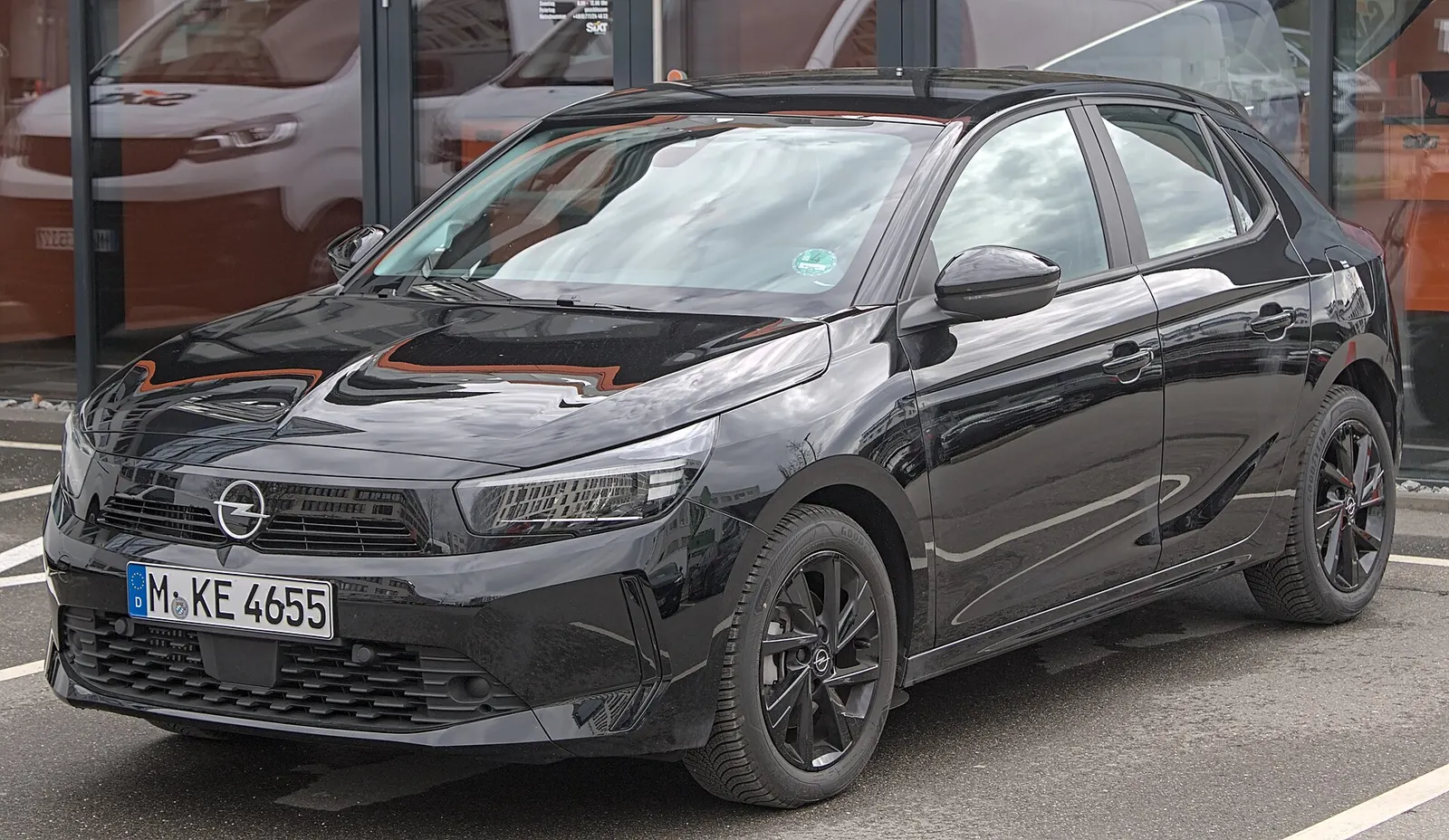 Opel Corsa F noire de 2023 de trois-quarts avant, garée devant une agence de location.