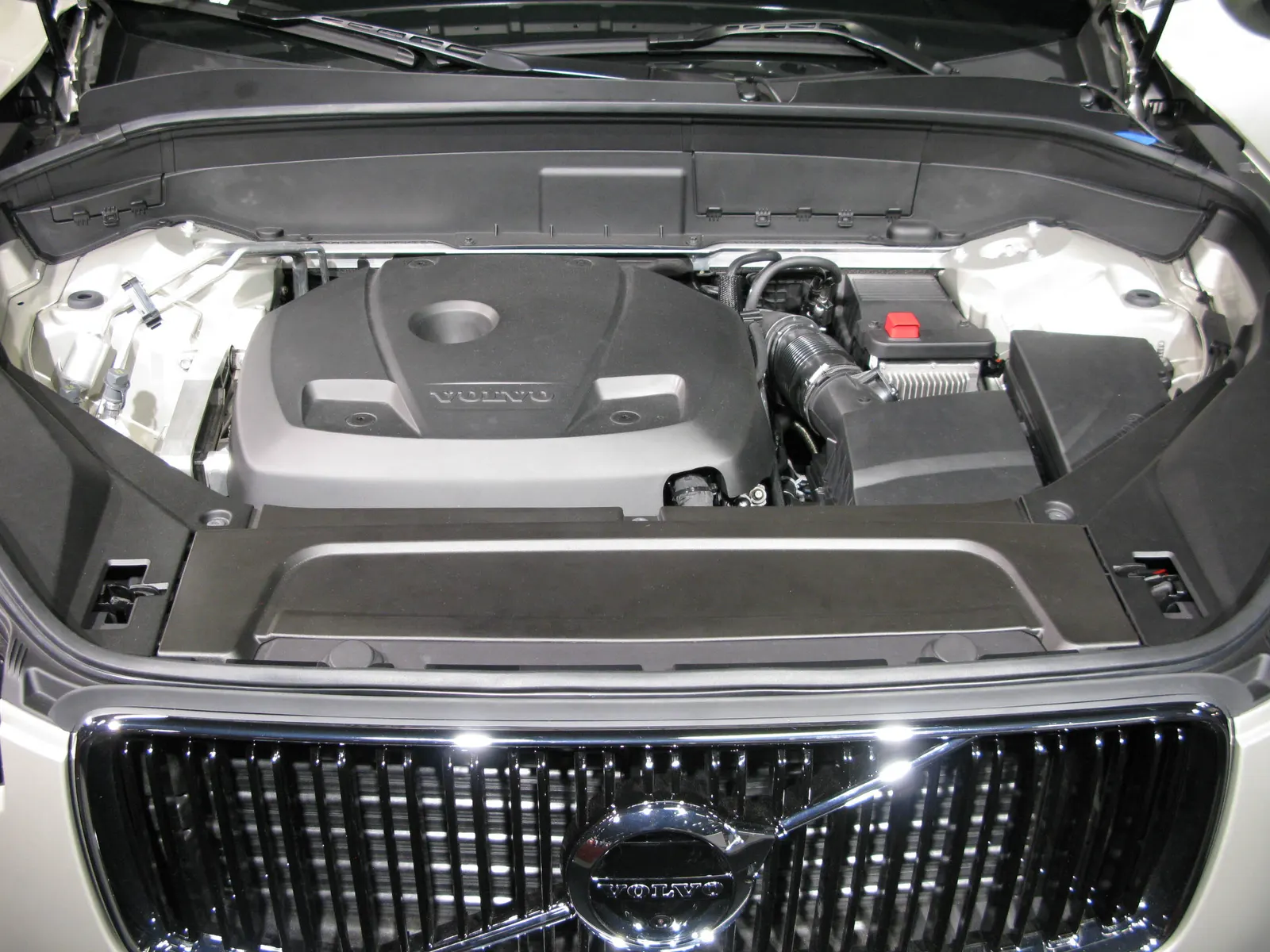 Compartiment moteur ouvert d'un Volvo XC90 II, calandre et logo Volvo visibles à l'avant.