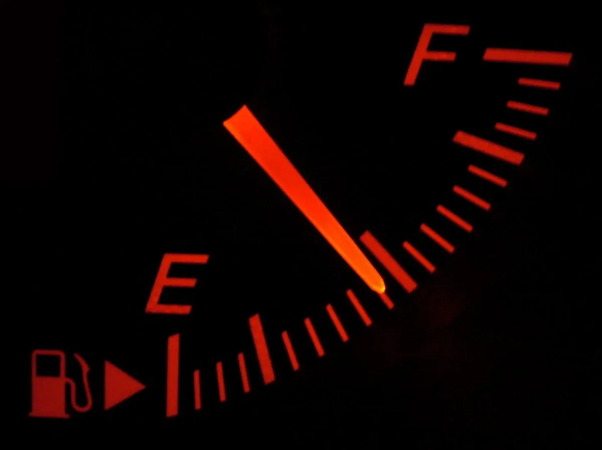 Jauge de carburant d'un tableau de bord automobile, aiguille rouge sur fond noir.
